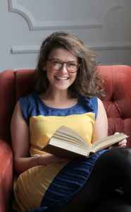 woman in blue and yellow dress sitting on red sofa